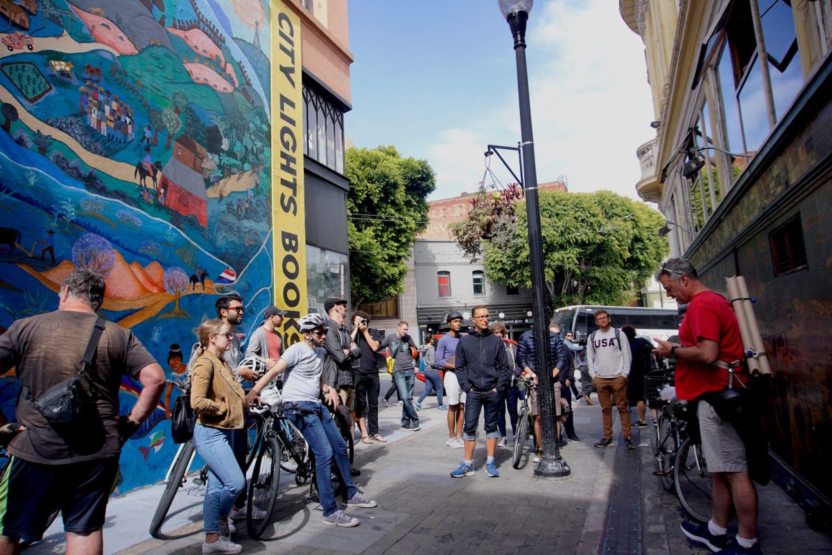 Large Group of bicycle riders standing outside City Lights Bookstore.