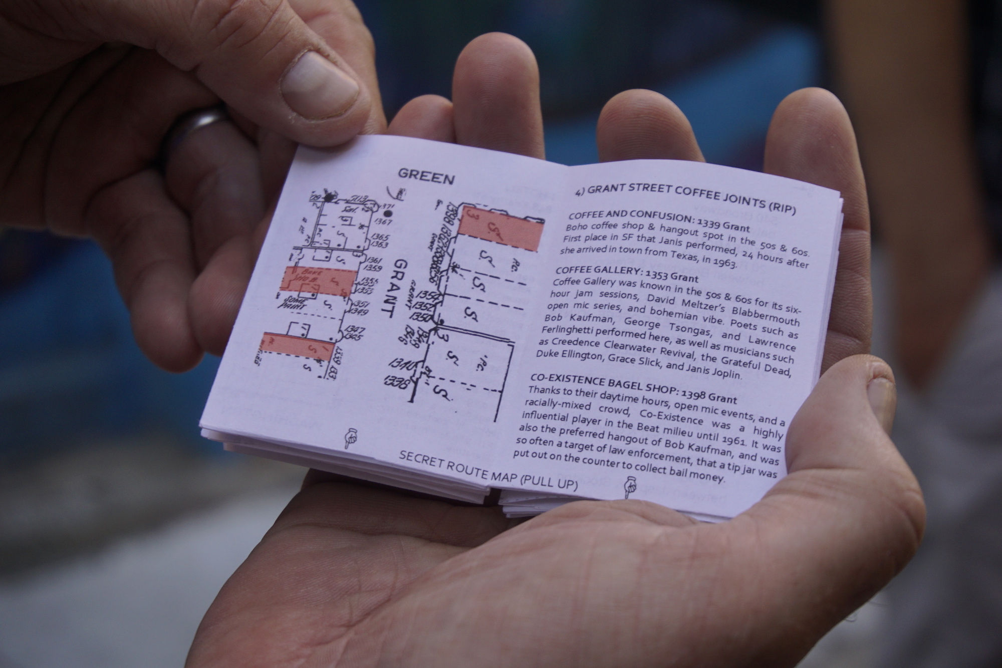 A pair of hands holding a small zine, opened to a page entitled Grant Street Coffee Joints (RIP)